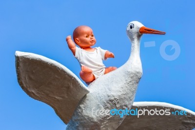 Baby Doll Sitting On Stork With Blue Sky Stock Photo