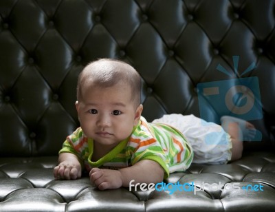 Baby Lying On Sofa Bed With Eyes Contact To Camera Stock Photo