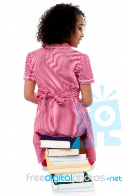 Back Pose Of A Girl Sitting On A Pile Of Books Stock Photo