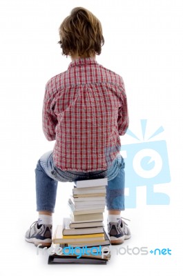 Back Pose Of Boy Sitting On Books Stock Photo