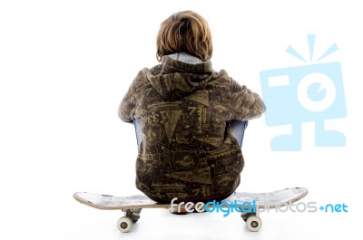 Back Pose Of Boy Sitting On Skate Stock Photo