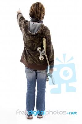 Back Pose Of Pointing Boy Holding Skateboard Stock Photo