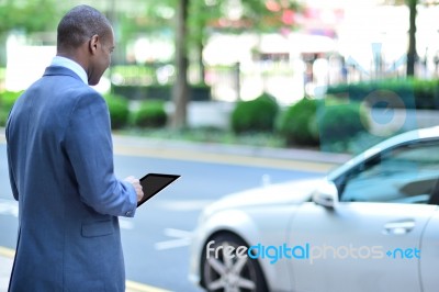 Back View Of African Man Holding Tablet Stock Photo