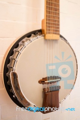 Banjo Hanging On White Brick Wall Stock Photo