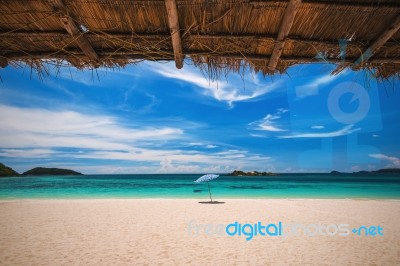 Beach Umbrella With Emerald Sea On A Sunny Day, Island In Background, Thailand Stock Photo