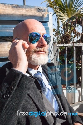 Bearded Businessman With Sunglasses Talking On Smartphone Stock Photo