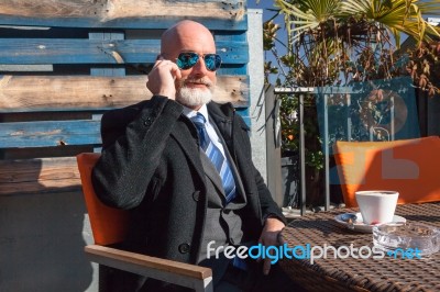 Bearded Businessman With Sunglasses Talking On Smartphone Stock Photo