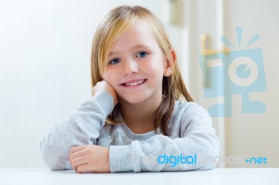 Beautiful Blonde Child Sitting At A Table In Kitchen Stock Photo