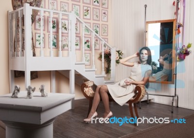 Beautiful Girl In A Bright Dress Sitting On A Chair Stock Photo