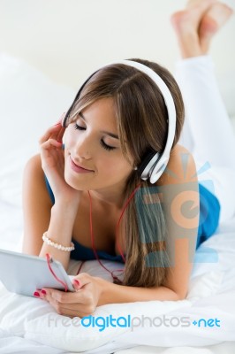 Beautiful Girl Listening To Music With Tablet On Sofa At Home Stock Photo