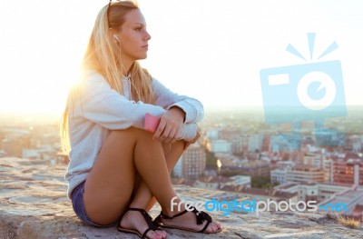 Beautiful Girl Sitting On The Roof And Listening To Music Stock Photo