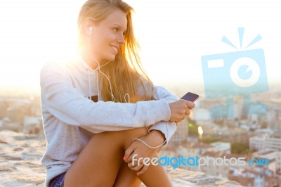 Beautiful Girl Sitting On The Roof And Listening To Music Stock Photo