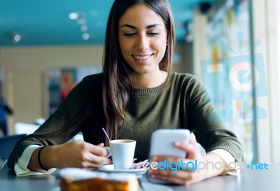 Beautiful Girl Using Her Mobile Phone In Cafe Stock Photo