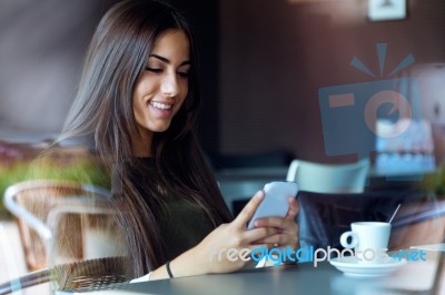 Beautiful Girl Using Her Mobile Phone In Cafe Stock Photo