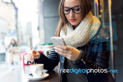 Beautiful Girl Using Her Mobile Phone In Cafe Stock Photo