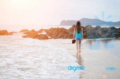 Beautiful Girl Walking On The Beach At Sunset Stock Photo