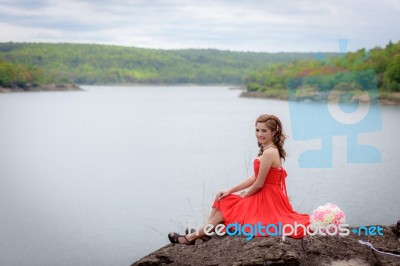 Beautiful Red Dress Girl Sitting On The River And Mountains Stock Photo