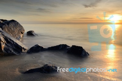 Beautiful Seascape Of Wave And Rock On Beach With Sunrise Stock Photo