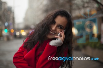 Beautiful Smiling Woman In Red Coat With Mobile Phone In Hands, Stock Photo