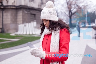 Beautiful Woman In Red Coat And Wool Cap And Gloves With Smartph… Stock Photo