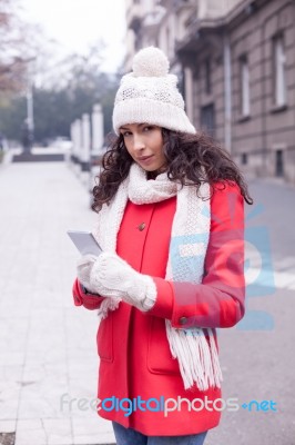 Beautiful Woman In Red Coat And Wool Cap And Gloves With Smartph… Stock Photo