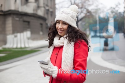 Beautiful Woman In Red Coat And Wool Cap And Gloves With Smartph… Stock Photo