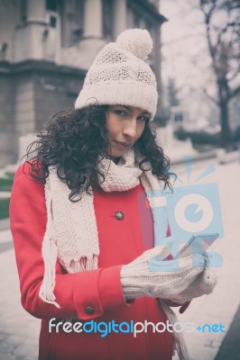 Beautiful Woman In Red Coat And Wool Cap And Gloves With Smartph… Stock Photo