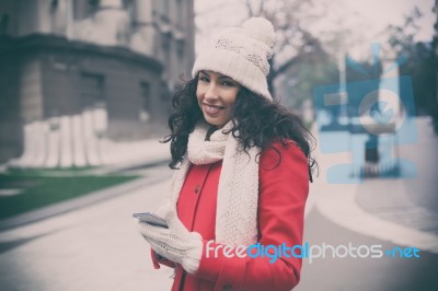 Beautiful Woman In Red Coat And Wool Cap And Gloves With Smartph… Stock Photo