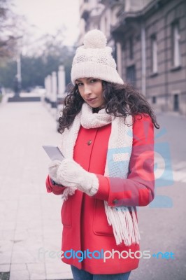 Beautiful Woman In Red Coat And Wool Cap And Gloves With Smartph… Stock Photo