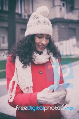 Beautiful Woman In Red Coat And Wool Cap And Gloves With Smartph… Stock Photo