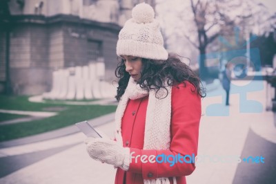 Beautiful Woman In Red Coat And Wool Cap And Gloves With Smartph… Stock Photo