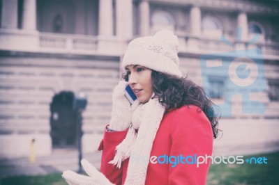 Beautiful Woman In Red Coat And Wool Cap And Gloves With Smartph… Stock Photo