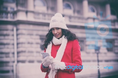 Beautiful Woman In Red Coat And Wool Cap And Gloves With Smartph… Stock Photo