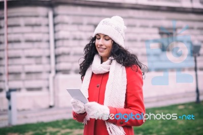 Beautiful Woman In Red Coat And Wool Cap And Gloves With Smartph… Stock Photo