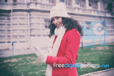 Beautiful Woman In Red Coat And Wool Cap And Gloves With Smartph… Stock Photo