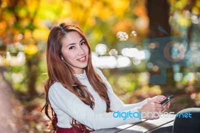 Beautiful Woman Smiling And Hand Holding Smartphone In Fall Forest Park Stock Photo