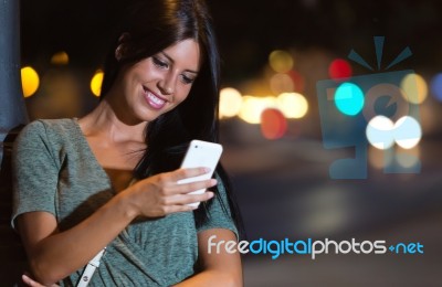 Beautiful Woman Use Her Phone In The City At Night Stock Photo