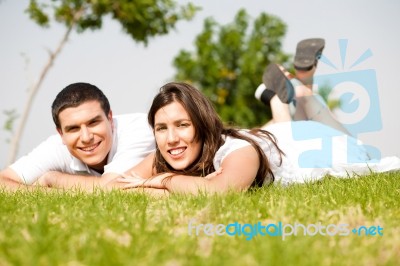 Beautiful Young Couple Lie Down On Grass Stock Photo