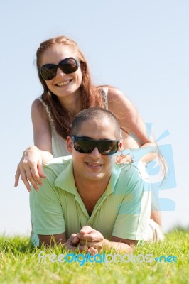 Beautiful Young Couple Lie Down On Grass Stock Photo