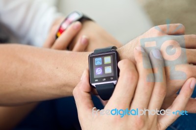 Beautiful Young Couple Using A Smartwatch At Home Stock Photo