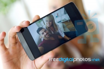 Beautiful Young Couple Using Mobile Phone At Home Stock Photo