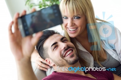 Beautiful Young Couple Using Mobile Phone At Home Stock Photo