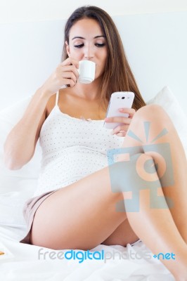 Beautiful Young Woman Drinking Coffee And Using Mobile Phone On Stock Photo