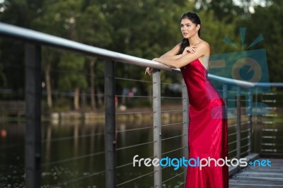 Beautiful Young Woman In The Gardens Wearing A Long Silk Red Dress Stock Photo