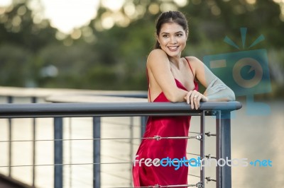 Beautiful Young Woman In The Gardens Wearing A Long Silk Red Dress Stock Photo