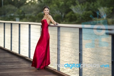 Beautiful Young Woman In The Gardens Wearing A Long Silk Red Dress Stock Photo