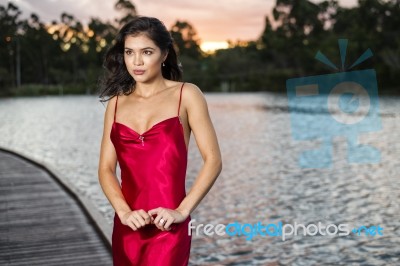 Beautiful Young Woman In The Gardens Wearing A Long Silk Red Dress Stock Photo