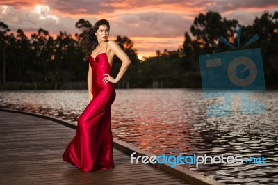 Beautiful Young Woman In The Gardens Wearing A Long Silk Red Dress Stock Photo