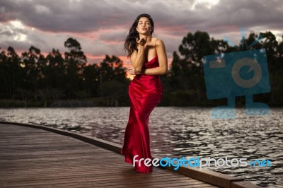 Beautiful Young Woman In The Gardens Wearing A Long Silk Red Dress Stock Photo