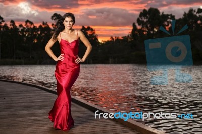 Beautiful Young Woman In The Gardens Wearing A Long Silk Red Dress Stock Photo